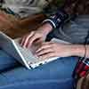 膝の上でノートパソコンを使う女性